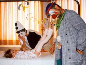 2 hopiclowns jouant avec un enfant malade sur son lit